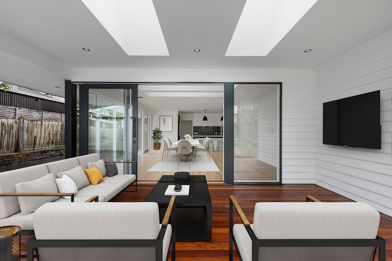 Modern living space with outdoor seating area and view into indoor dining room.