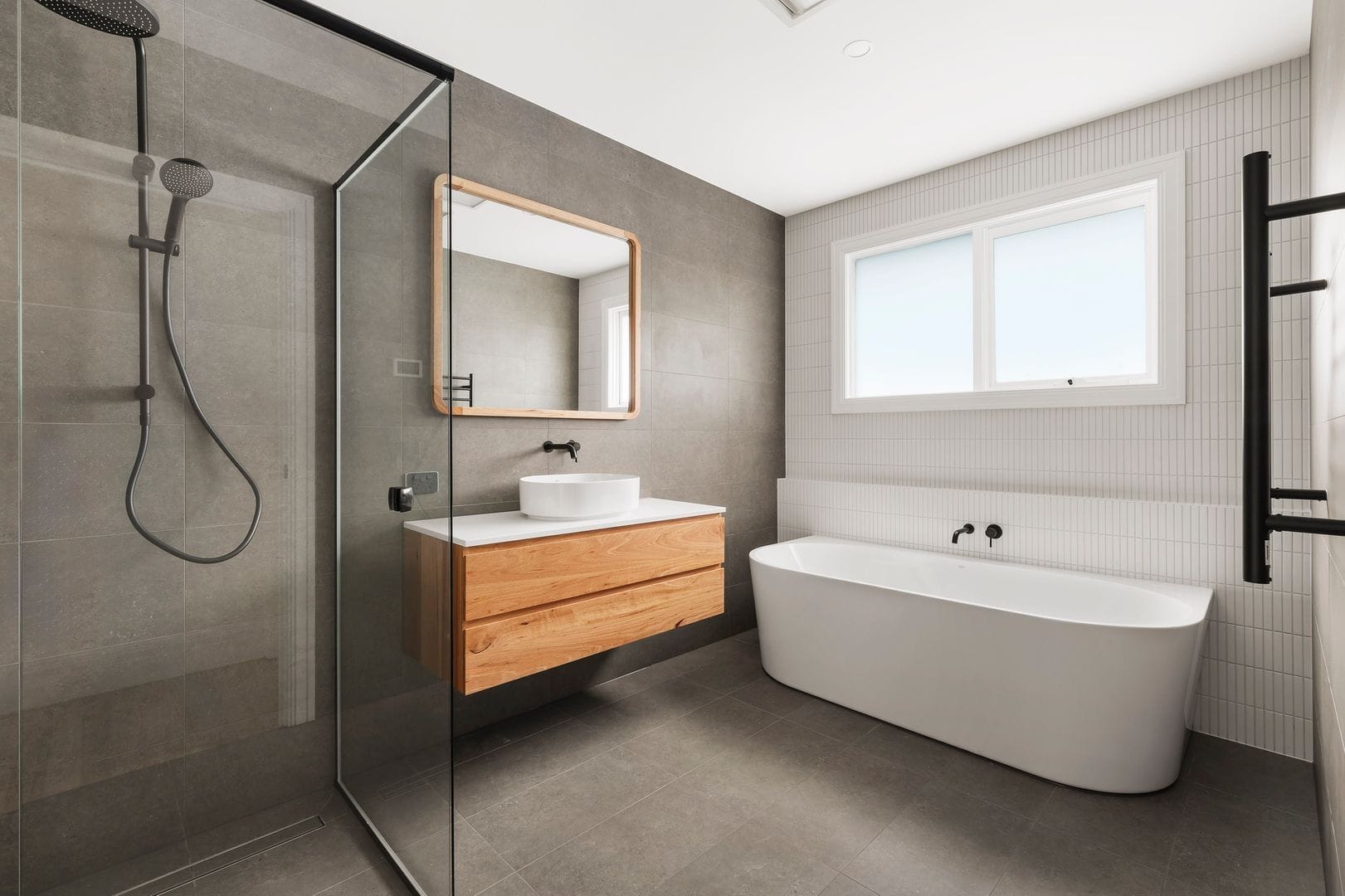 Modern bathroom with glass shower, wooden vanity, and freestanding bathtub