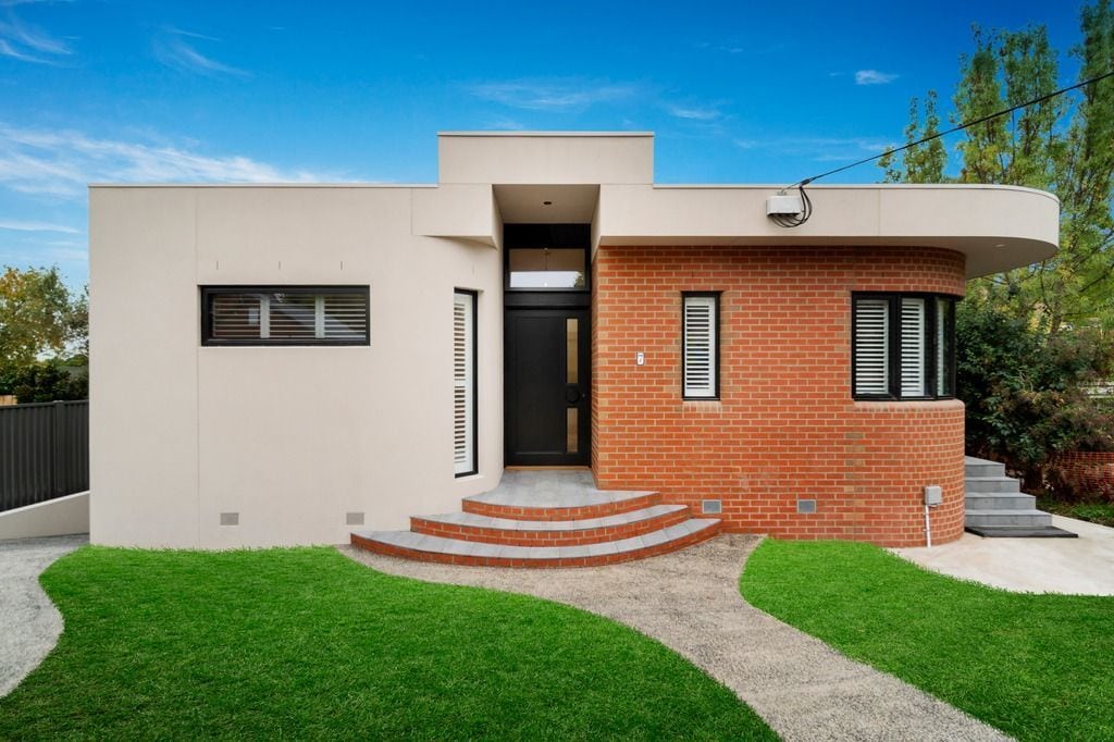 Front view of a modern double-story house in Eaglemont with Austral red bricks and beige walls.