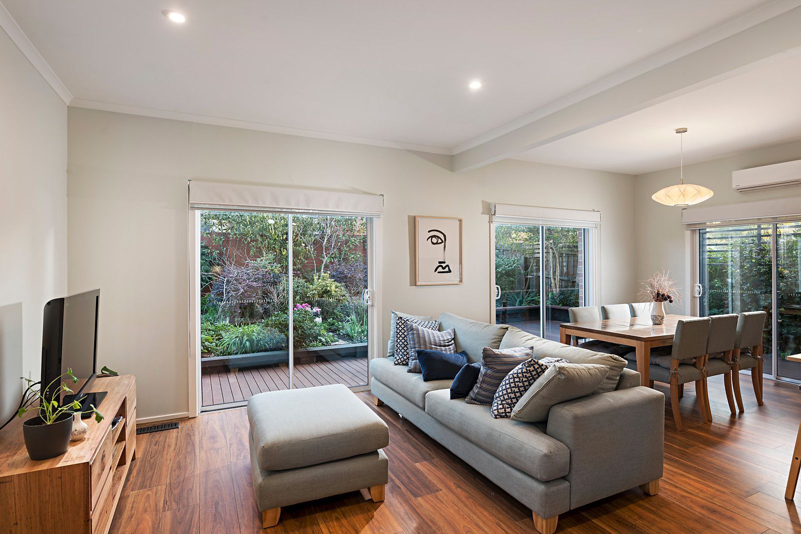 Living room with grey sofa, wooden furniture, and sliding glass doors leading to a garden